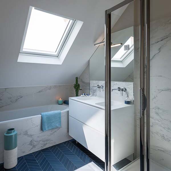 Salle de bain blanche avec effet marbre et tapis bleu